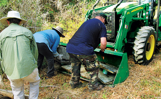 Team members lead debris onto the tractor