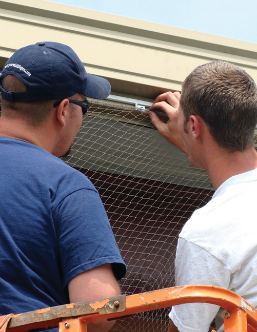 Blue Ridge Wildlife & Pest Management General Manager Cedric Short, left, lets a client see how StealthNet is attached. PHOTO: BLUE RIDGE WILDLIFE & PEST MANAGEMENT