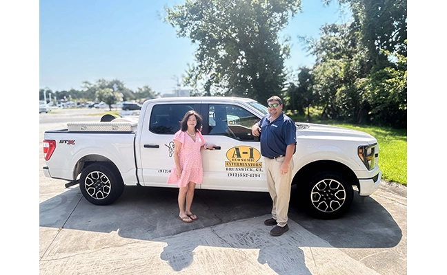 Former owner and new owner stand in front of truck