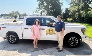 Former owner and new owner rep stand in front of truck